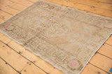 Distressed vintage Oushak rug corner, antique ivory field, pale pink geometric border.