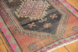 Distressed vintage Oushak rug showing abrashed charcoal field and blush hook and latch motifs.