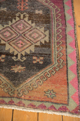 Corner of distressed Oushak rug, bubblegum pink border, hook and latch motif on abrashed charcoal field.