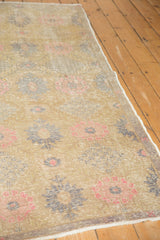 Vintage distressed Oushak rug with splayed floral motif, ivory, slate silver, blush pink, and worn pile.