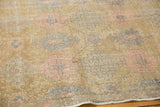 Distressed vintage Oushak rug texture, revealing blush pink and slate floral motifs on low pile.