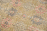 Distressed Oushak rug's worn texture, blush pink and slate floral motifs, with visible foundation.