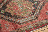 Distressed cherry red Oushak rug pile showing wear and charcoal-green medallion details.