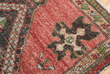 Vintage distressed Oushak rug showing cherry red field, visible foundation, charcoal, beige, and green pattern.