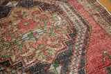 Distressed vintage Oushak rug with cherry red, beige, charcoal navy patterns. Foundation shows through.
