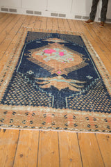 Distressed vintage Oushak rug showing indigo blue pile, beige border, and prominent wear.