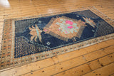 Detail of distressed Oushak rug, showing worn texture, faded copper borders, and floral finial.
