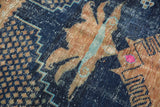 Distressed indigo blue Oushak rug detail with pale copper floral motifs and visible foundation.