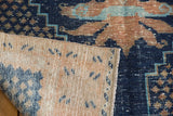 Folded corner of vintage Oushak rug showing hand-knotted foundation and distressed indigo pile.