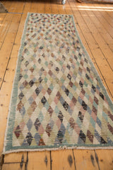 Distressed Oushak runner end with intact selvage, fringe, and worn diamond pattern.