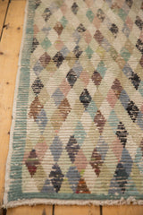 Distressed Oushak runner's worn lattice diamond pattern with intact side selvage.