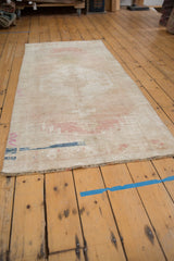 Distressed vintage Oushak runner end with low pile, abrashed ivory, blush, and indigo tones.