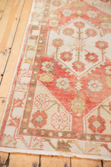 Vintage distressed Oushak rug runner texture, soft blush and ivory floral motifs, aged pile.