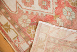 Distressed vintage Oushak runner with blush, rose, ivory floral design and visible foundation.