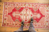 Distressed Oushak runner with cherry red geometric medallion and bursting florals.