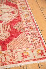 Textural detail of distressed cherry red Oushak pile, ivory lattice spandrel, and fringe.