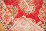 Vintage distressed Oushak rug corner revealing wear, red pile, and hand-knotted woven foundation.