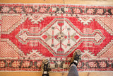 Detail of vintage distressed Oushak runner; red diamond medallion, geometric floral patterns, ivory tones.