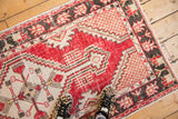 Distressed cherry red Oushak rug runner with geometric ivory patterns, highlighting texture and wear.