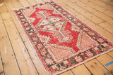 Geometric lattice corner spandrel and distressed cherry red field of the vintage Oushak runner.