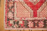 Cherry red, ivory lattice corner spandrel, dark geometric border, and fringe of distressed Oushak rug.