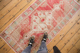 Distressed Oushak rug runner with faded blush red, ivory, and pale aqua geometric patterns.