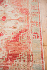 Distressed texture of vintage Oushak runner, blush red geometric pattern and pale aqua border.