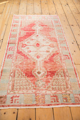 Distressed vintage Oushak rug runner with faded red, ivory, and pale aqua geometric motifs.
