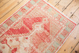 Close-up of vintage Oushak runner corner with distressed blush red pile, ivory, and pale aqua geometric spandrels.