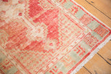 Distressed Oushak rug showing blush red, ivory, and pale aqua geometric border.