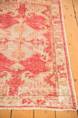 Distressed raspberry red and ivory Oushak rug pile, visible foundation, soft luster, fringed end.