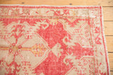 Distressed vintage Oushak rug corner, raspberry red and ivory reciprocating motif, visible foundation.