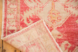 Distressed Oushak rug pile in raspberry and ivory, revealing secure edge and reverse foundation.