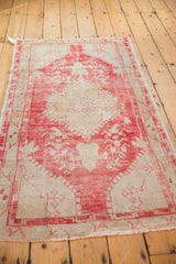 Distressed Oushak rug corner, showing faded raspberry scalloped contour and floral field.