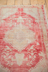 Distressed vintage Oushak rug, showing worn raspberry red and ivory floral motifs with foundation.