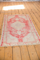 Distressed corner of a vintage Oushak rug, showcasing blush and ivory hues and secured fringe.
