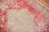Worn vintage Oushak rug showcasing a blush floral lattice and meandering vine border.