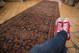 Long vintage Hamadan runner with allover Herati motif, deep navy, red tones, and tattered sides.