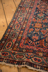 Vintage Hamadan rug corner, showing red Serbend border, colorful Herati pattern, worn pile, and tattered fringe.