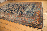 Vintage Mahal carpet's navy floral field, terra cotta vine palmette border, and tattered fringe.