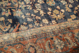 Detail of vintage Persian Mahal carpet with navy floral field and terra cotta border, showing hard wear to pile.