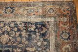 Vintage Mahal carpet corner detail: hard wear, tattered edge, navy, terra cotta floral design.