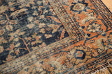 Detail of vintage Mahal rug's navy field, terra cotta palmette border, hard wear, and tattered fringe.