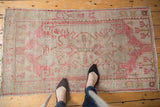 Distressed vintage Oushak rug with pale blush medallion, scrolling contours, and even wear.