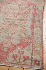 Pale blush and neutral patterns with intact side edge on distressed vintage Oushak rug.