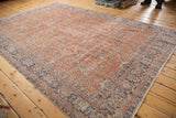 Distressed Oushak rug: soft red, ivory, and denim blue floral pattern with visible wear.