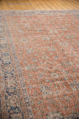 Angled close-up of distressed Turkish Oushak carpet showing soft red floral vinery and denim blue border.