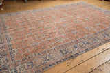 Distressed vintage Oushak rug, faded soft red pile reveals ivory foundation, denim blue vinery.