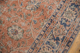 Distressed salmon pile of the vintage Oushak, showing denim blue border and floral vinery.