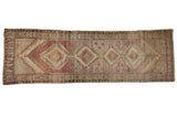 Distressed vintage Oushak runner with geometric medallions in aubergine, pale green, and ivory.